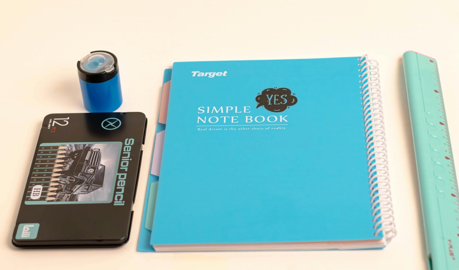 Flat lay of school supplies including notebook, pencils, and ruler on white background.