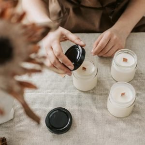 A close-up shot of a person making handmade candles in a cozy indoor workshop setting.